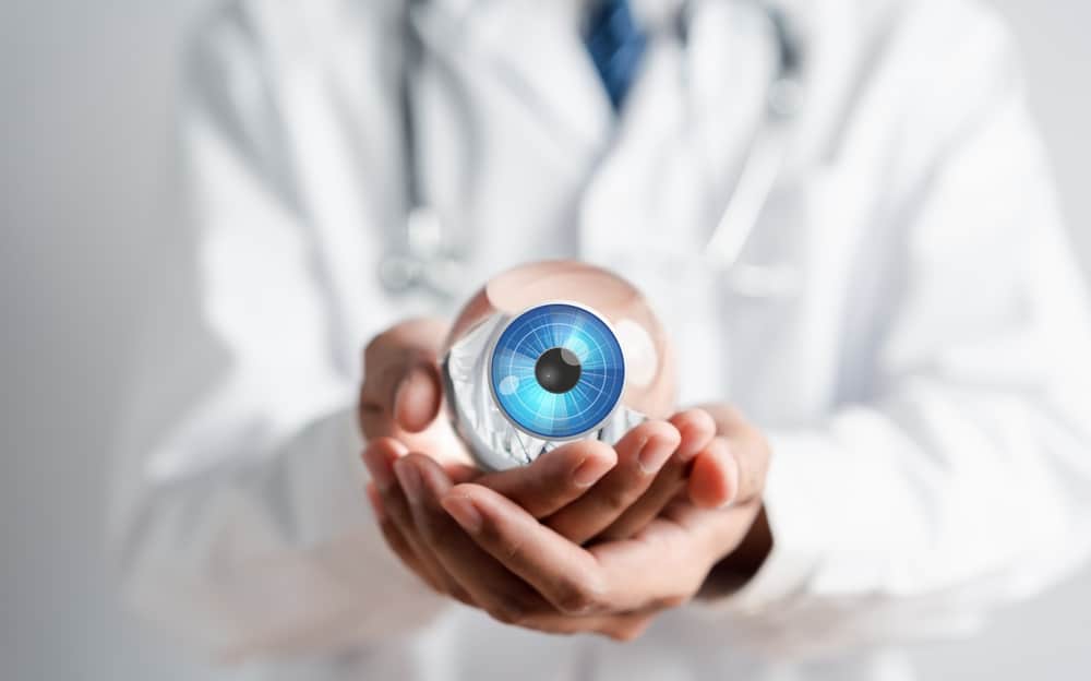 A clinician in a white coat holding a model of the human eye