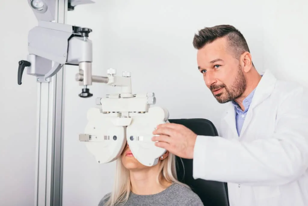 Optometrist adjusting a phoropter during a comprehensive vision examination
