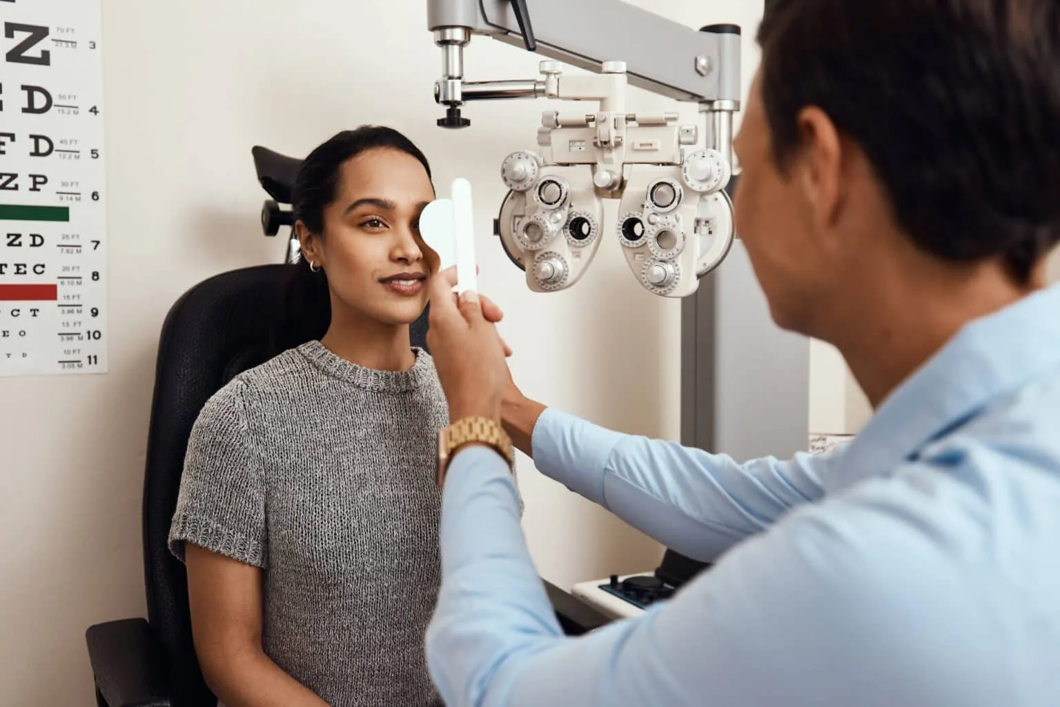 Optometrist performing a vision assessment using a phoropter during an eye examination