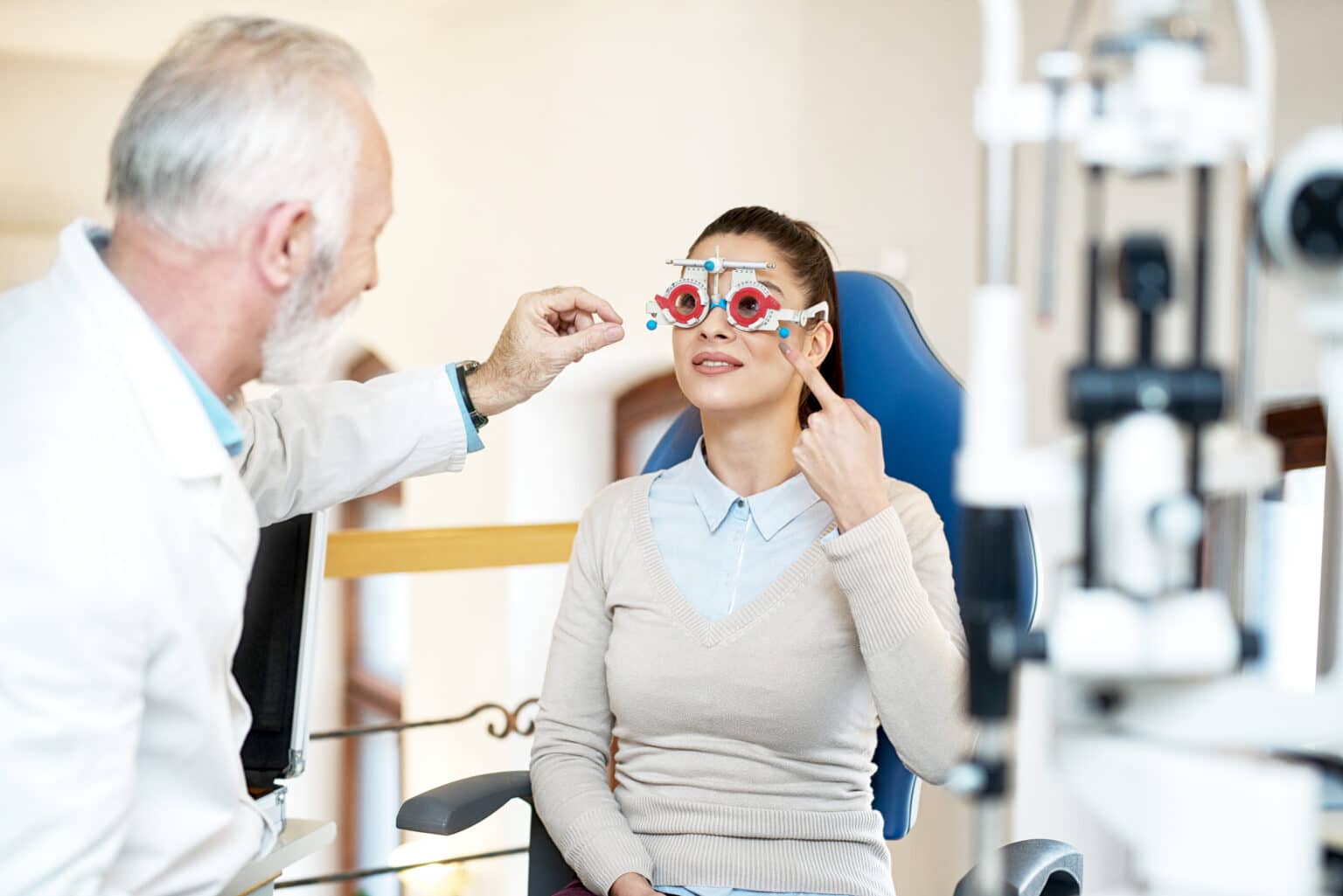 Optometrist adjusting a trial frame during a comprehensive eye examination with a patient