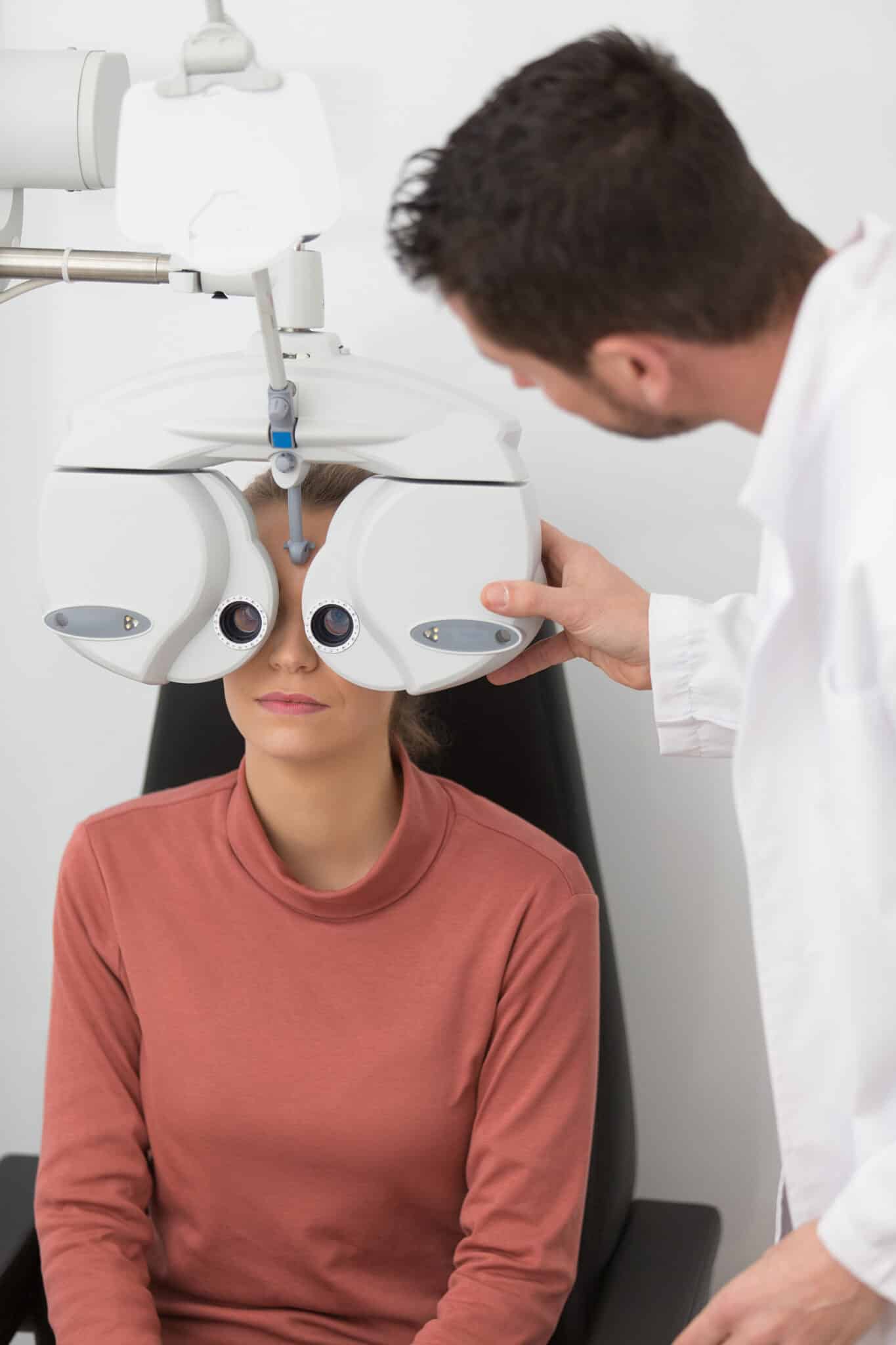 Optometrist adjusting a phoropter while performing a comprehensive eye examination